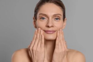 Woman with smooth, youthful skin touching her cheeks, showcasing Botox results for wrinkle reduction.
