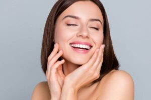 Woman smiling confidently with flawless skin, symbolizing the benefits of successful rhinoplasty preparation.