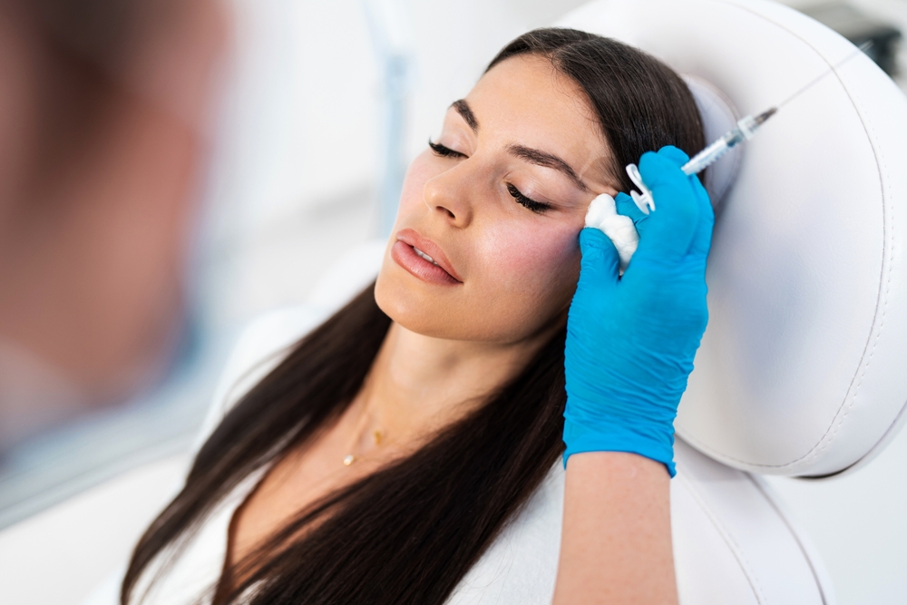 Woman receiving subtle facial filler injection at a clinic, highlighting trend toward natural cosmetic enhancements.