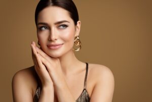 Woman with flawless skin gently touching face, representing early hours of Fraxel Dual recovery and sunburn sensation.