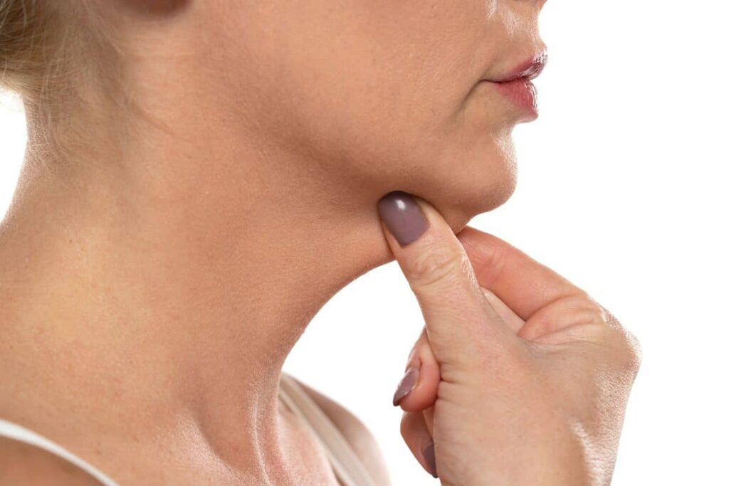 Woman pinching under her chin, illustrating skin laxity and volume loss from facial fat reduction during weight loss.