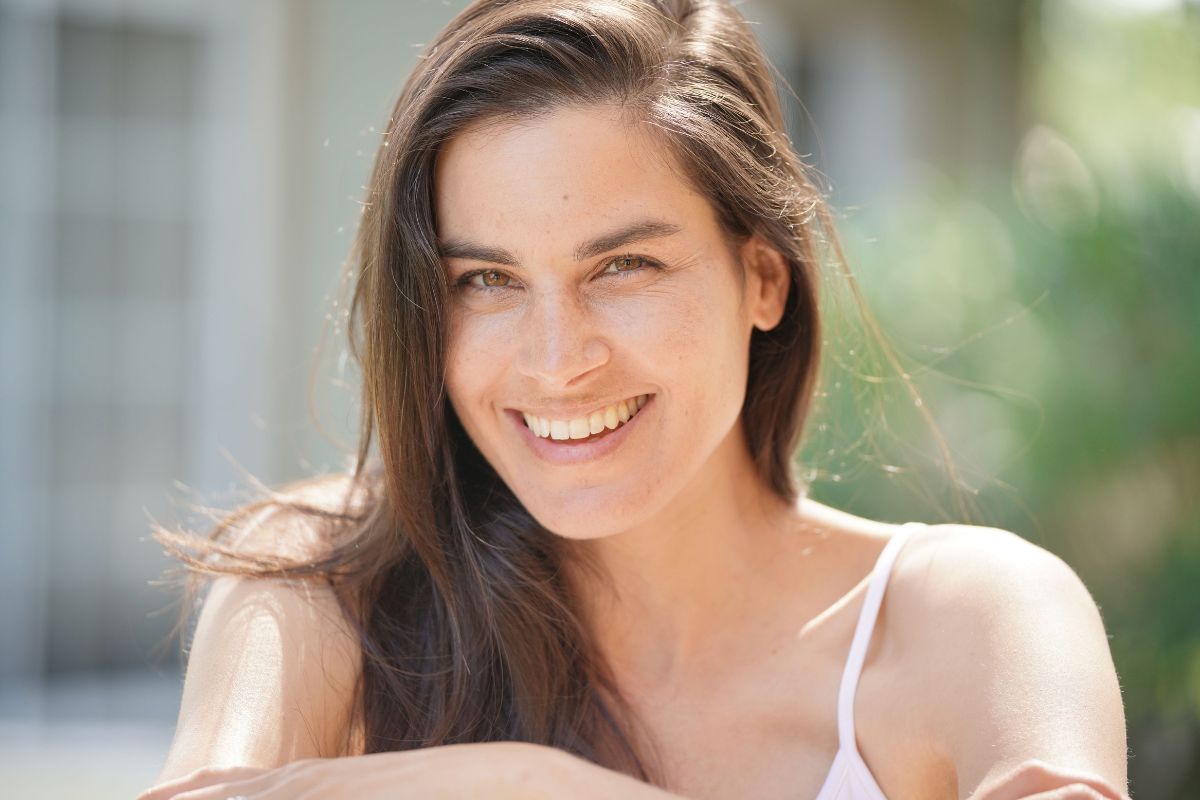 Woman smiling with full cheeks and smooth skin, representing non-filler facial volume restoration techniques